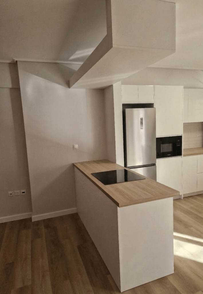 Custom σχεδιασμός λευκής κουζίνας με ξύλινο πάγκο και προσαρμογή σε δομικά στοιχεία χώρου - Kappawood