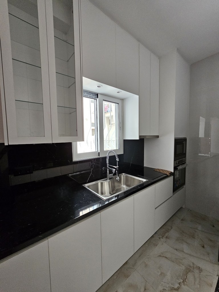 Μοντέρνα κουζίνα με λευκές ακρυλικές ματ επιφάνειες, πάγκο απομίμησης μαρμάρου και ψηλά ντουλάπια αποθήκευσης - Kappawood