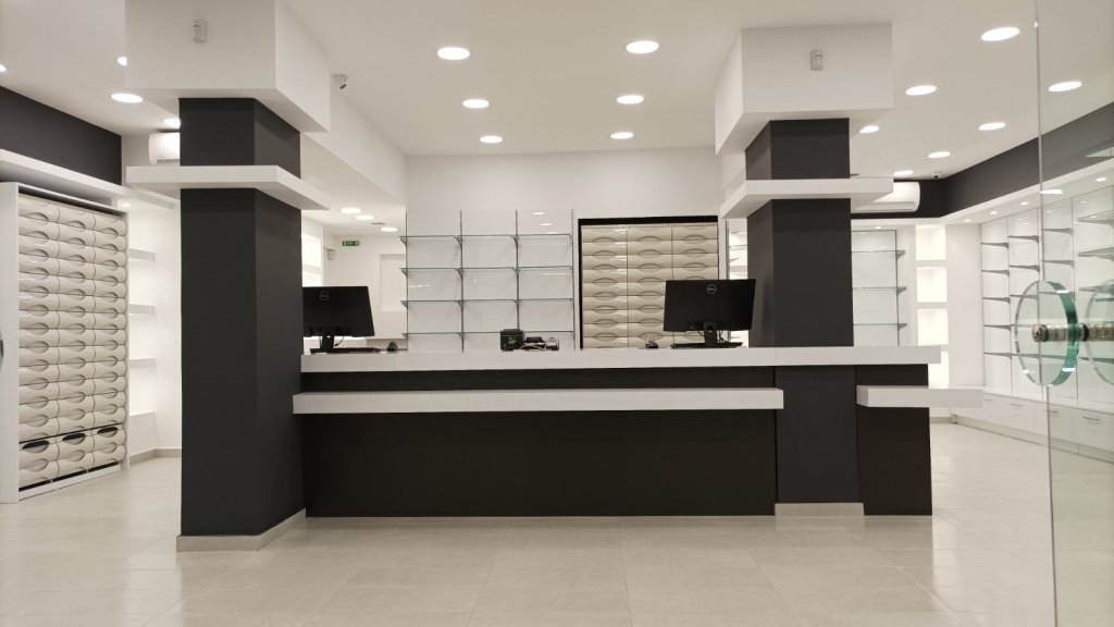 Ολοκληρωμένος εξοπλισμός μεγάλου φαρμακείου με λευκό γυαλιστερό ακρυλικό, ανθρακί λεπτομέρειες, κεντρικό πάγκο εργασίας και ενσωματωμένες συρταριέρες - Kappawood