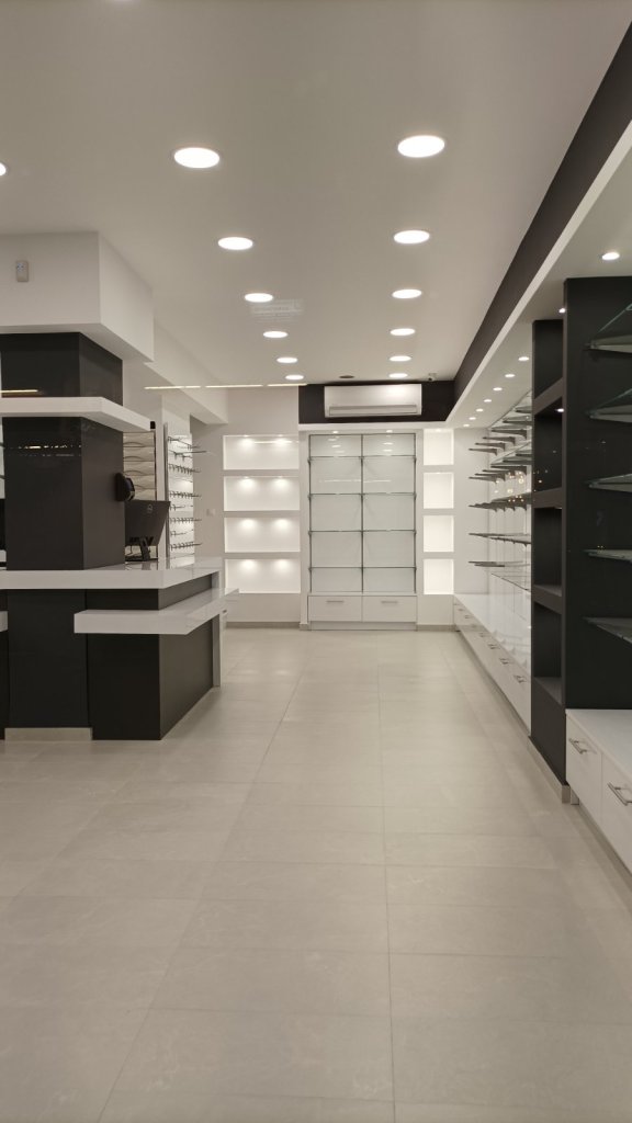 Ολοκληρωμένος εξοπλισμός μεγάλου φαρμακείου με λευκό γυαλιστερό ακρυλικό, ανθρακί λεπτομέρειες, κεντρικό πάγκο εργασίας και ενσωματωμένες συρταριέρες - Kappawood