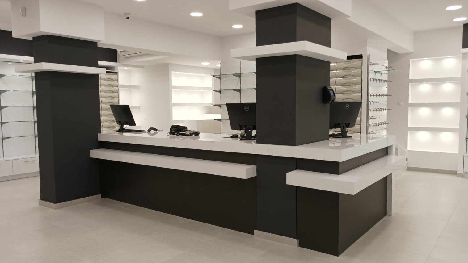 Ολοκληρωμένος εξοπλισμός μεγάλου φαρμακείου με λευκό γυαλιστερό ακρυλικό, ανθρακί λεπτομέρειες, κεντρικό πάγκο εργασίας και ενσωματωμένες συρταριέρες - Kappawood